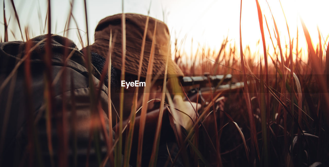 Man aiming rifle while lying on grassy field