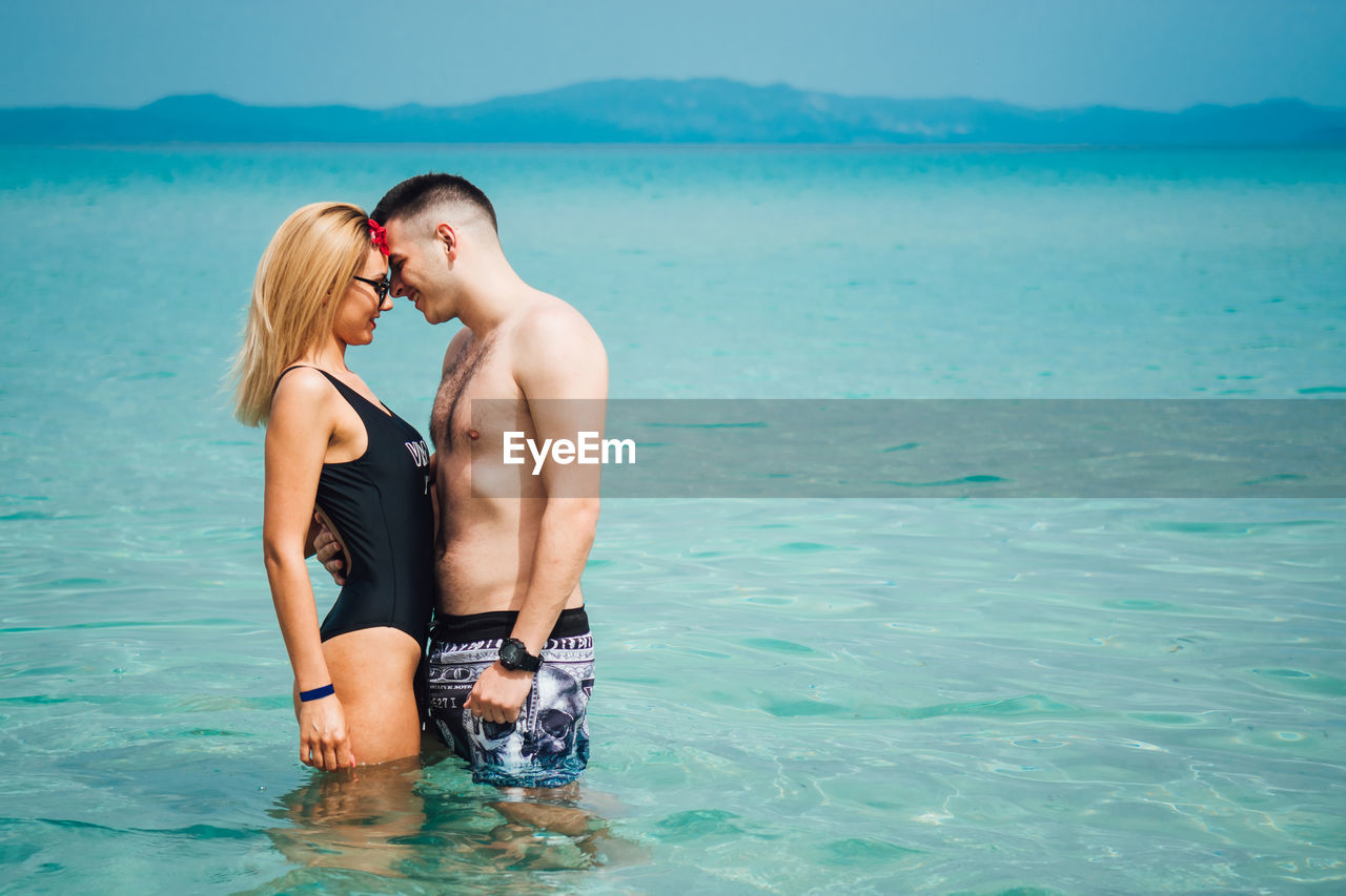 Young couple spending leisure time at beach against sky