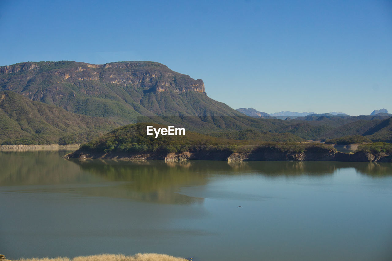 Scenic high view of lake and mountains against clear blue sky