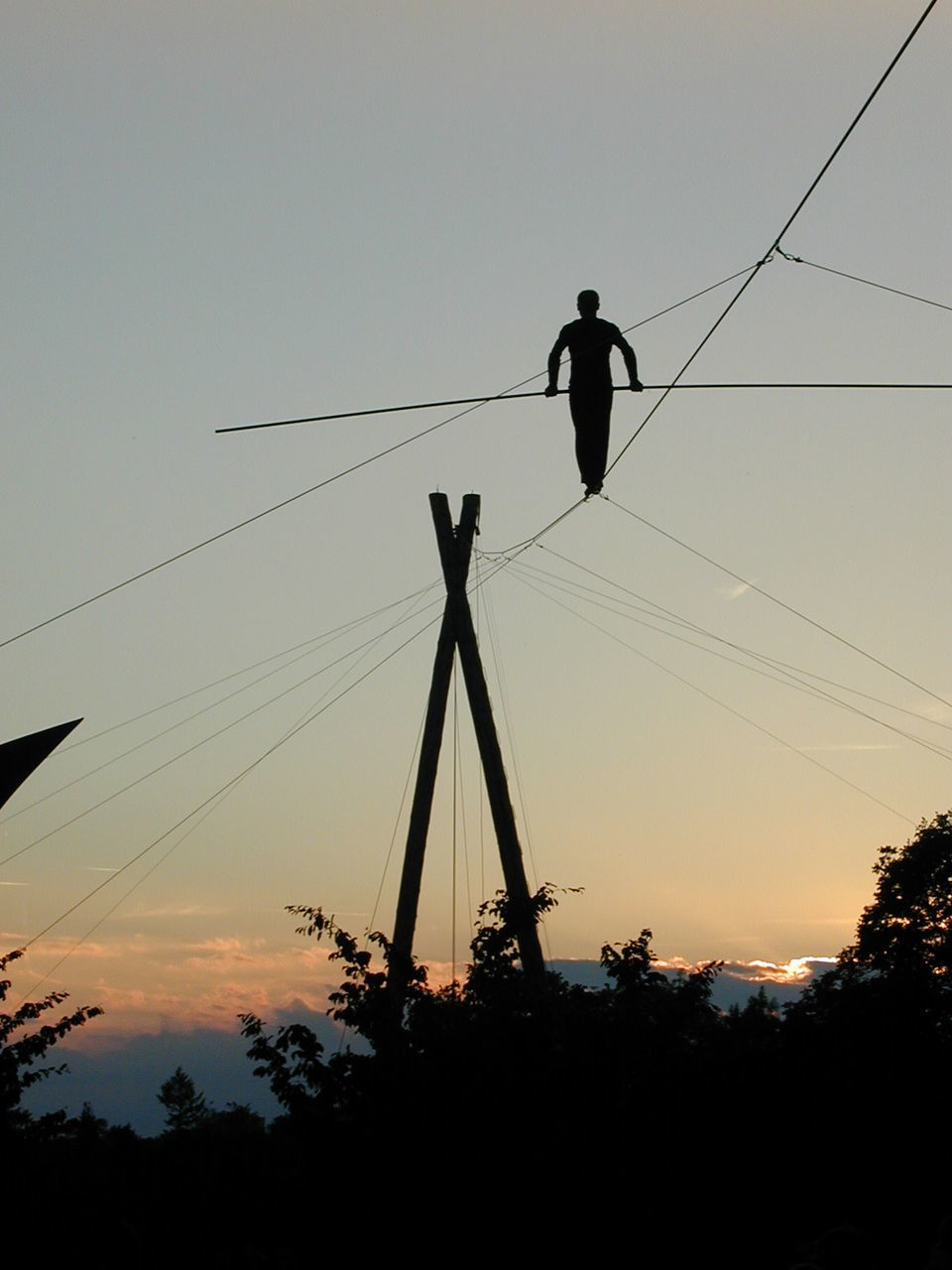 Silhouette person walking on rope against sky