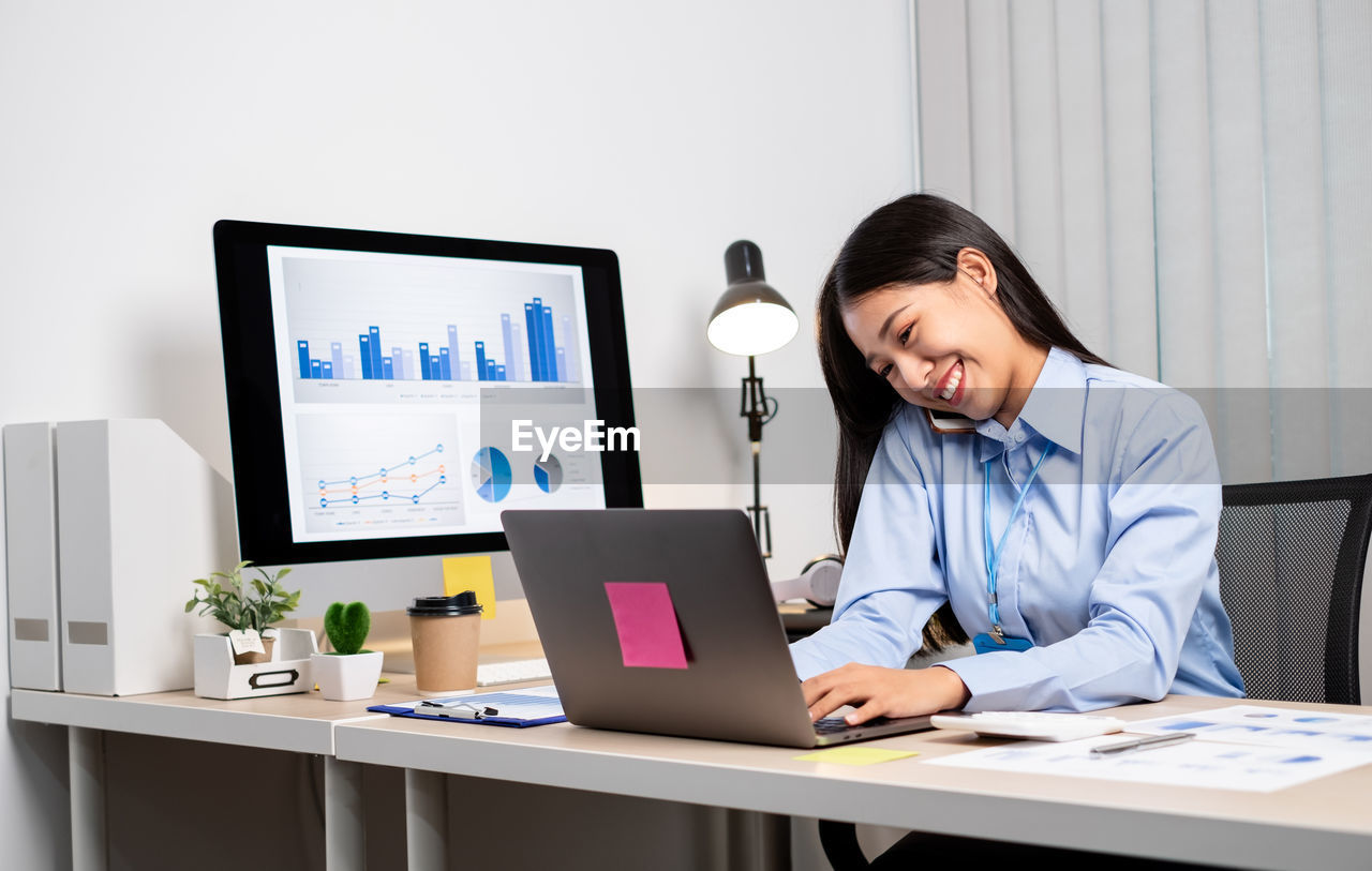 YOUNG WOMAN USING LAPTOP ON TABLE