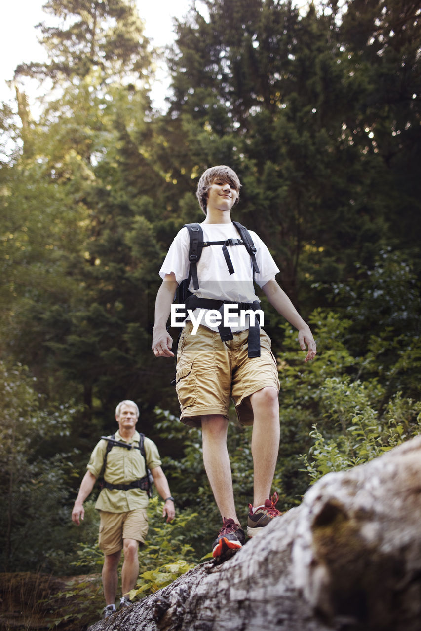 Son and father with on log in forest