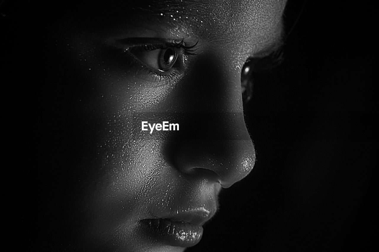 CLOSE-UP OF YOUNG WOMAN OVER BLACK BACKGROUND