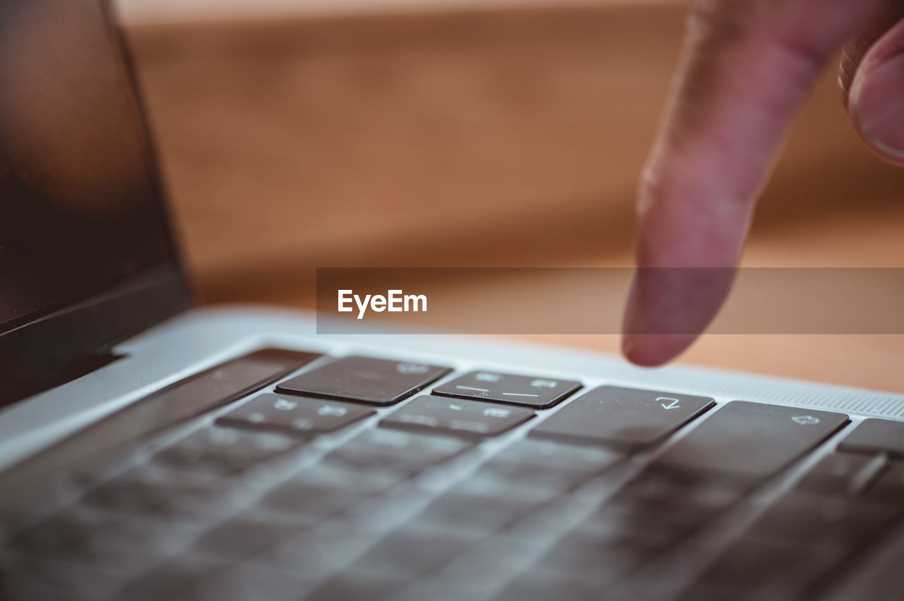 MIDSECTION OF MAN USING LAPTOP