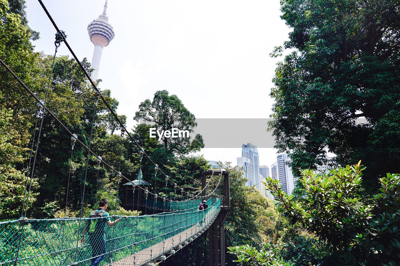 Footbridge in city against clear sky