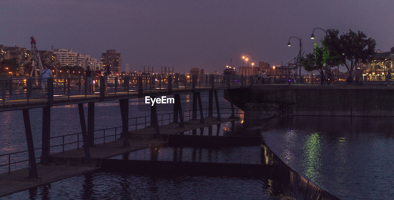 RIVER BY ILLUMINATED BUILDINGS AGAINST SKY AT NIGHT