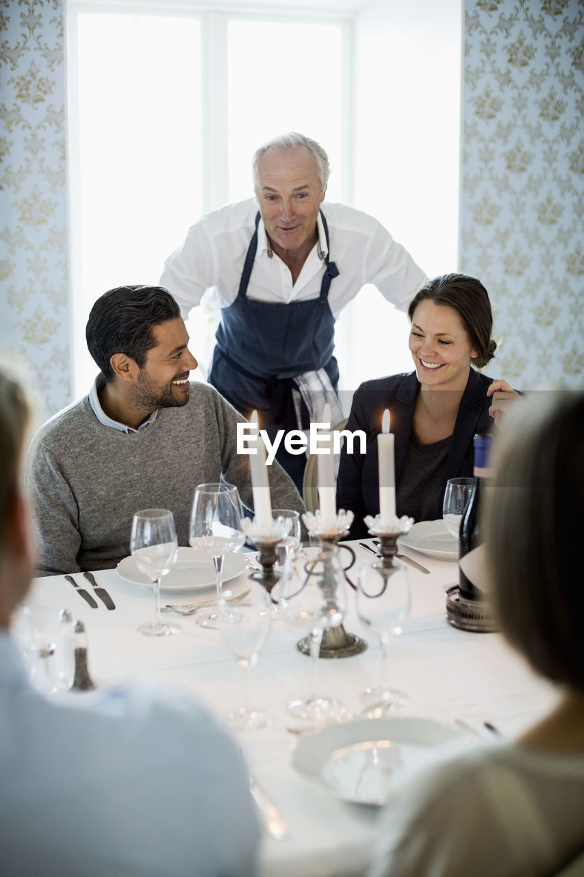 Senior chef talking to business people at dining table in restaurant
