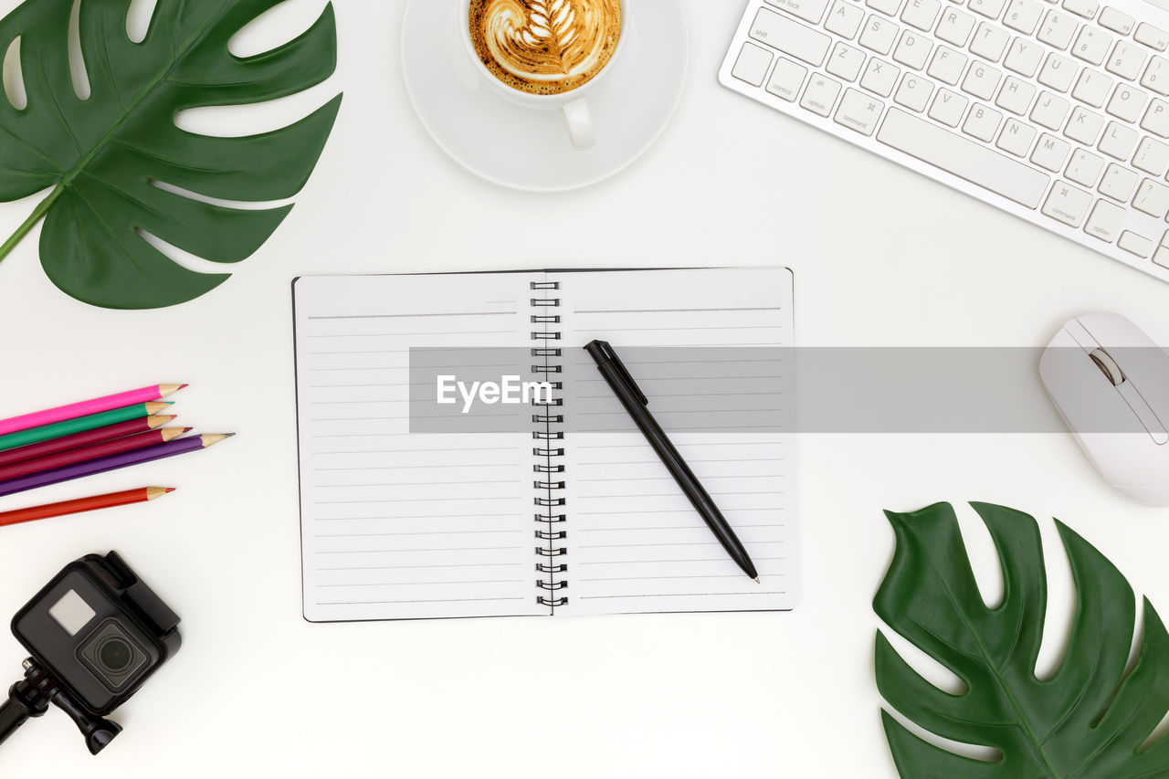 Directly above shot of book with pen and coffee on desk