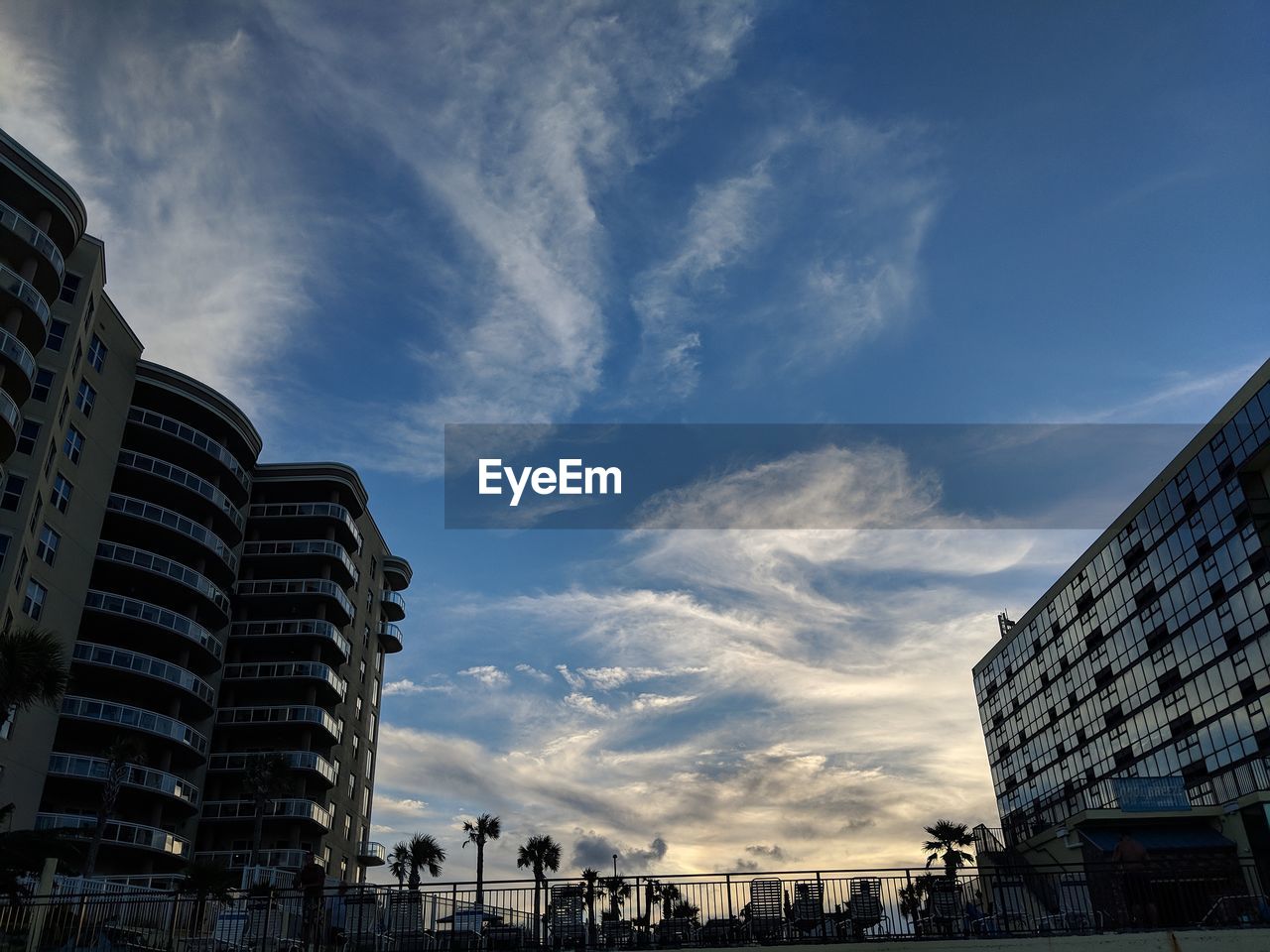 LOW ANGLE VIEW OF BUILDINGS IN CITY AGAINST CLOUDY SKY