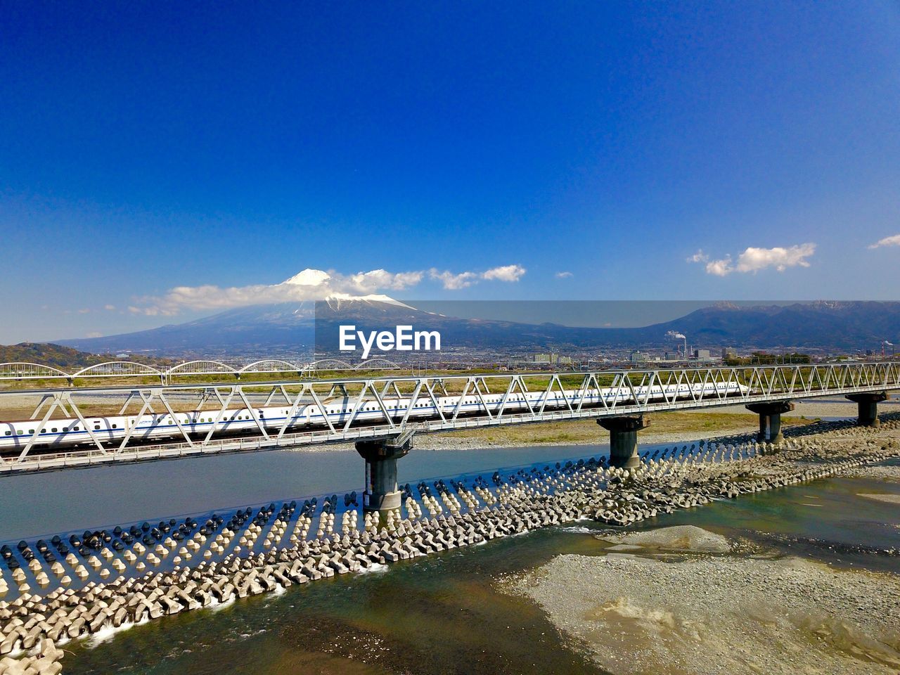 Bridge over sea against blue sky with mt. fuji and shinkansen