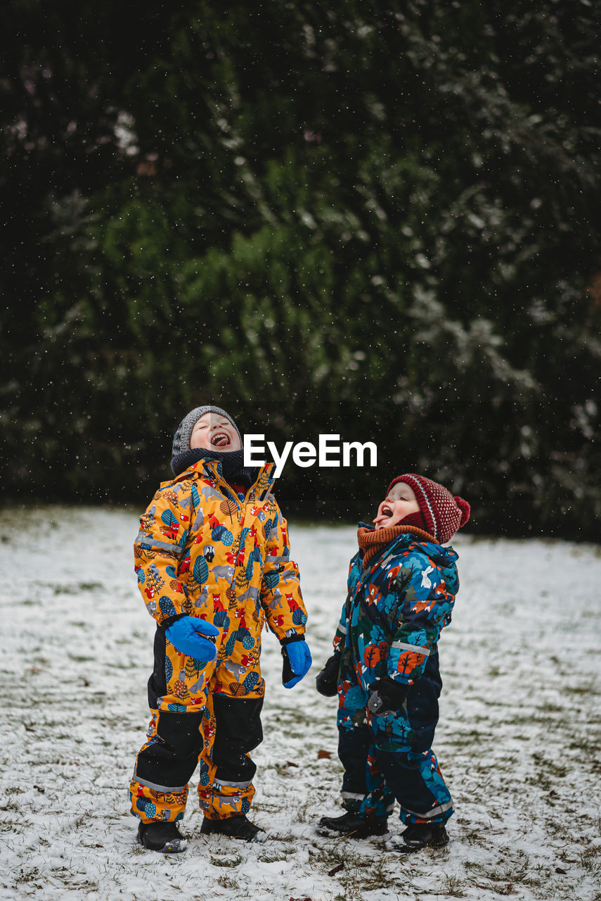 Fun children sticking tongue out to taste snowflakes on cold snowy day