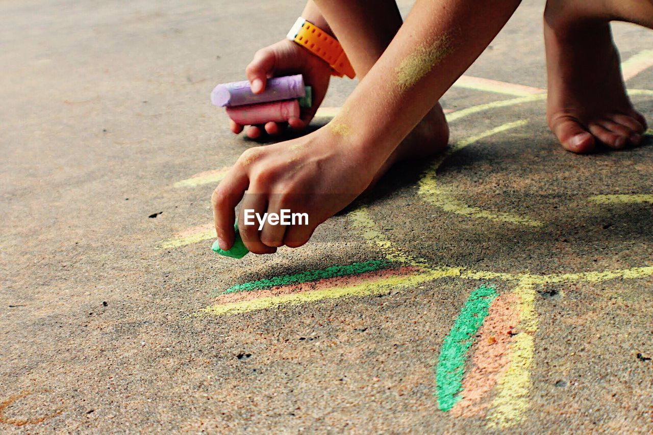 Low section of boy drawing with chalk on street