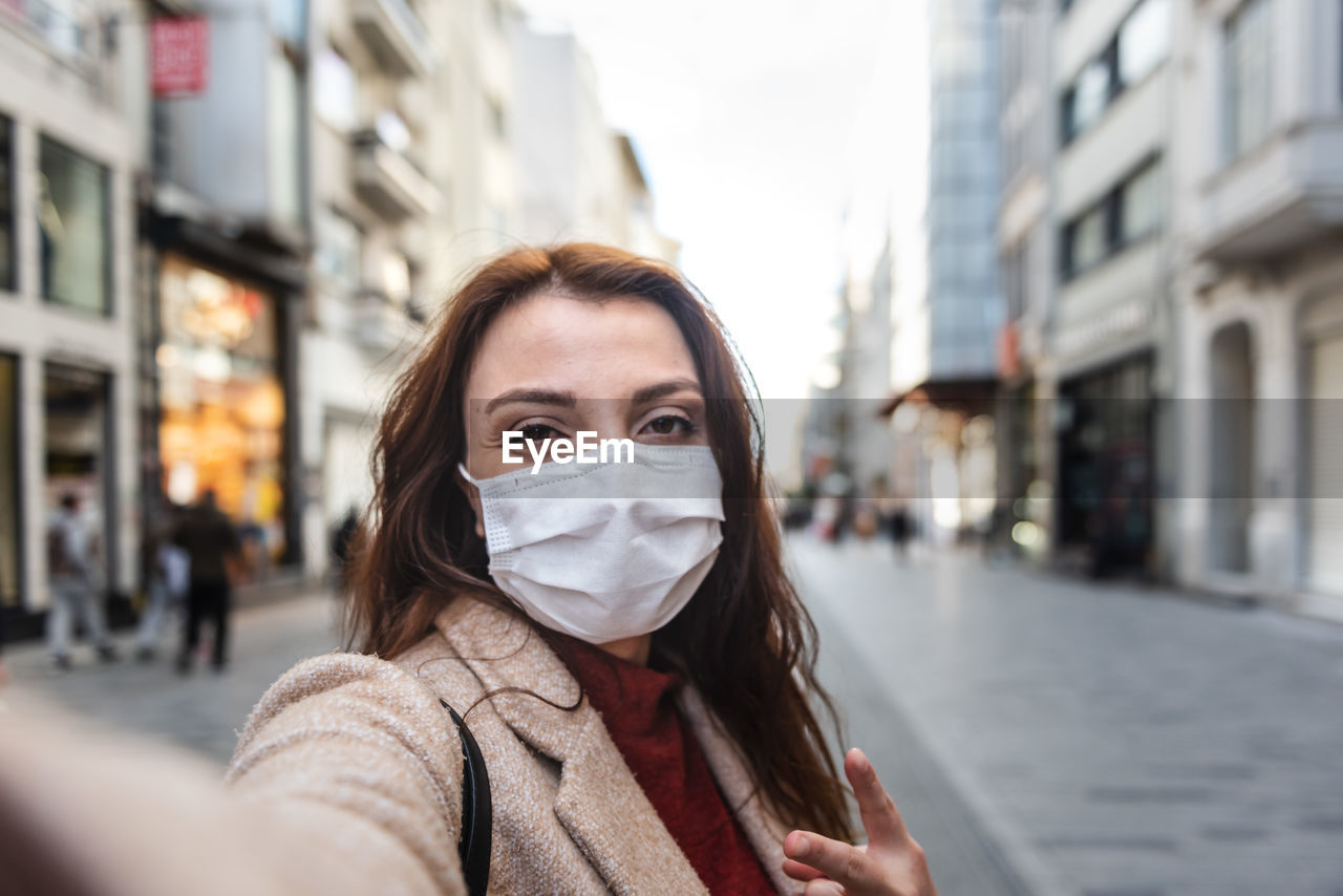 Portrait of woman wearing mask standing on city street