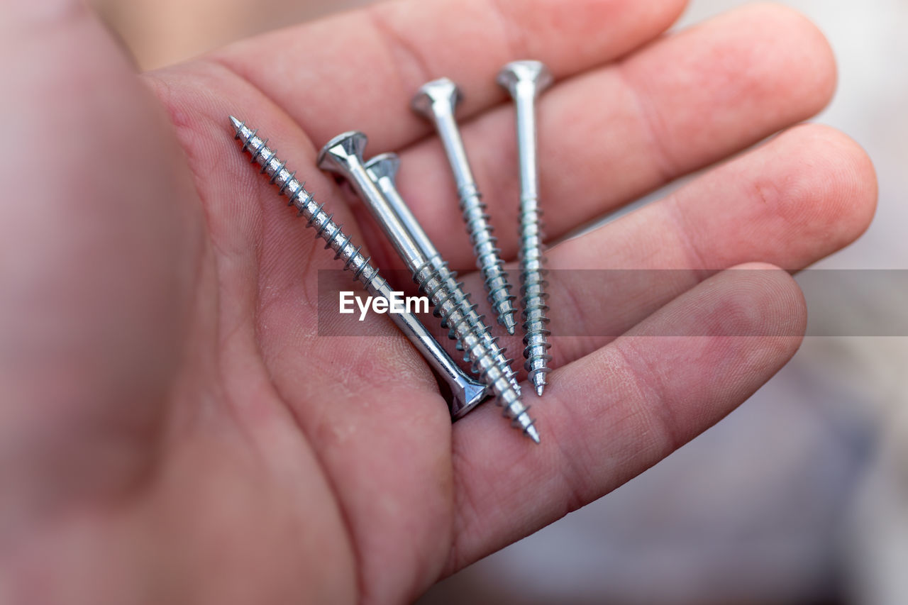 Close-up of hand holding screws