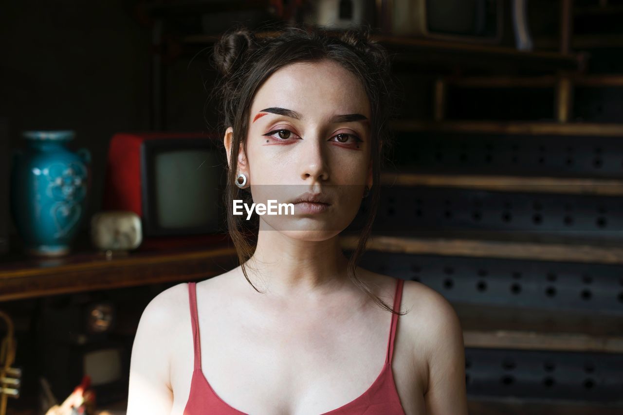 Close-up portrait of serious young woman with make-up at home