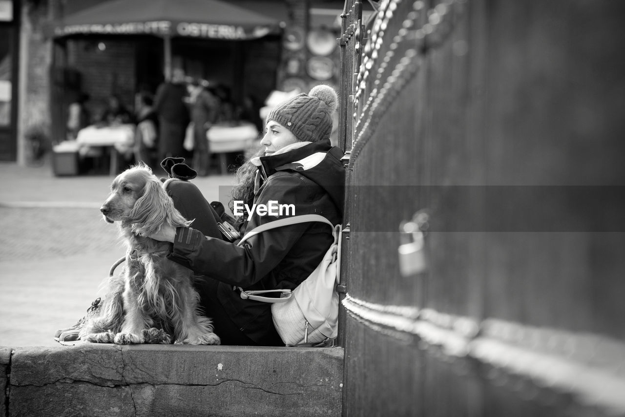 REAR VIEW OF MAN WITH DOG SITTING ON FLOOR