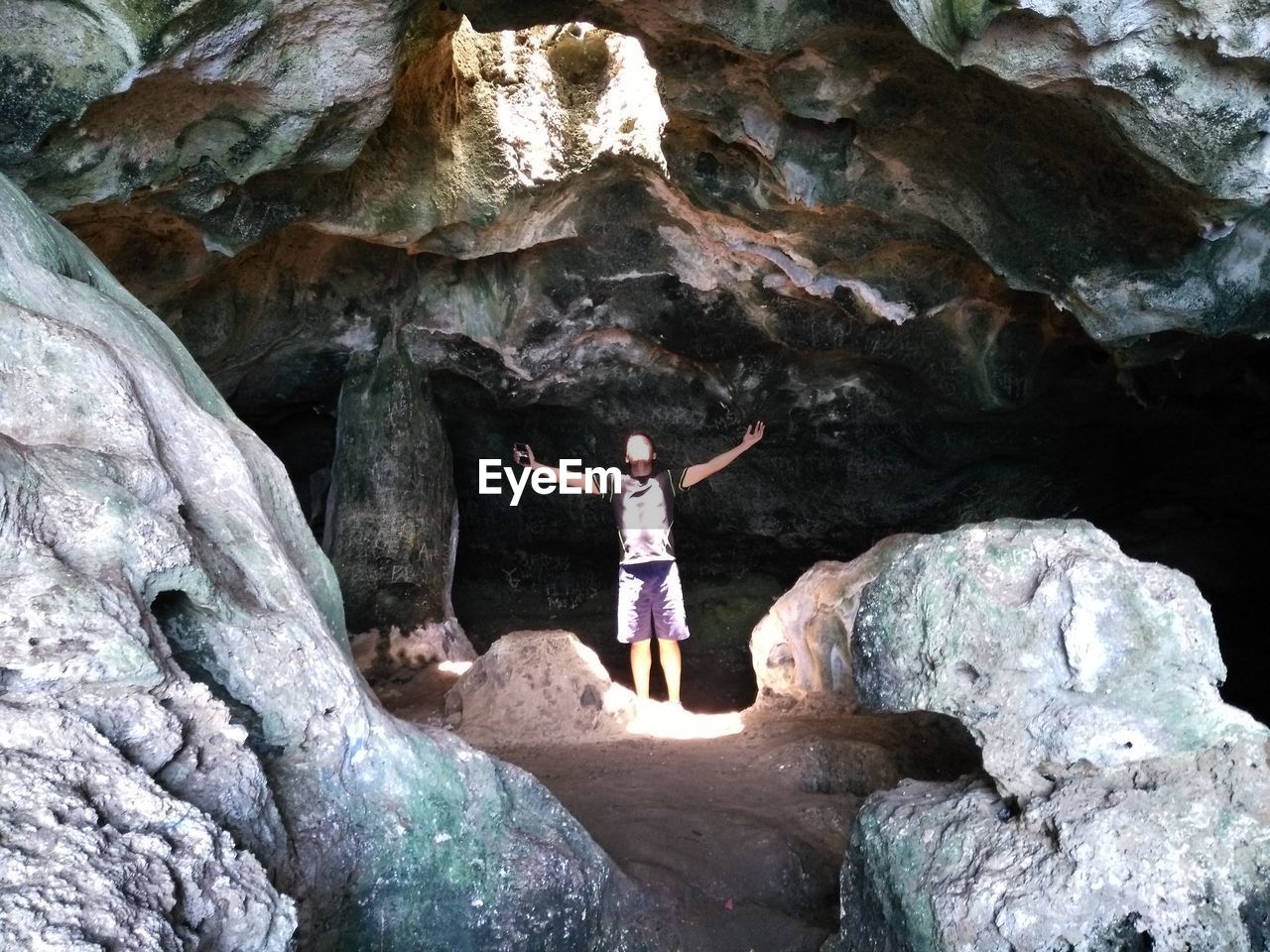 Low angle view of man with arms outstretched standing in cave