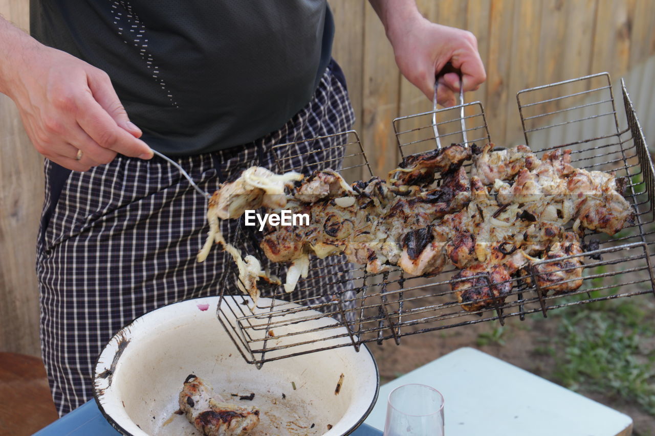 Midsection of man preparing food on barbecue grill