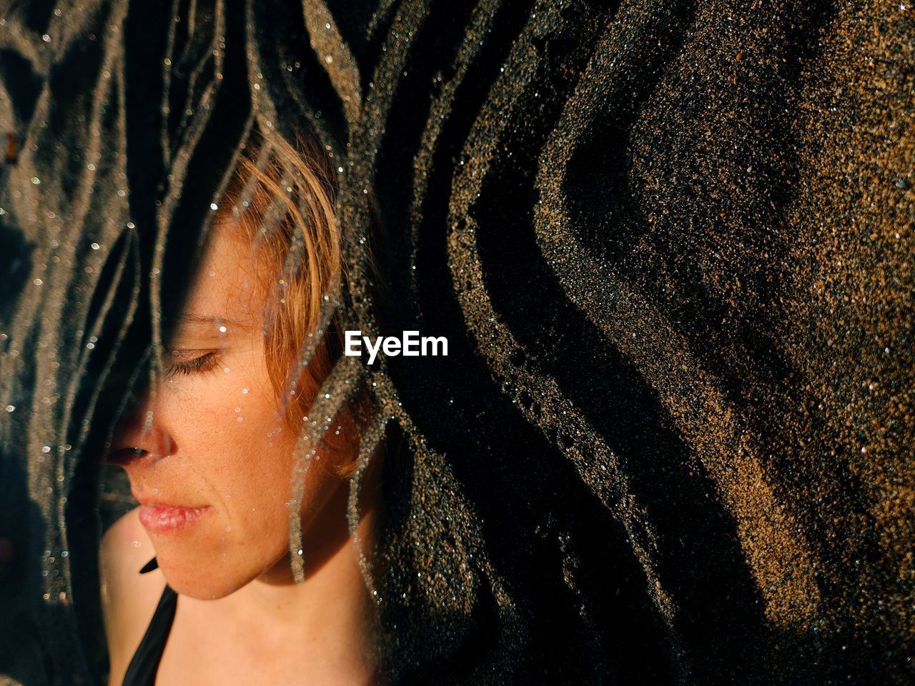 Close-up portrait of woman with sand background