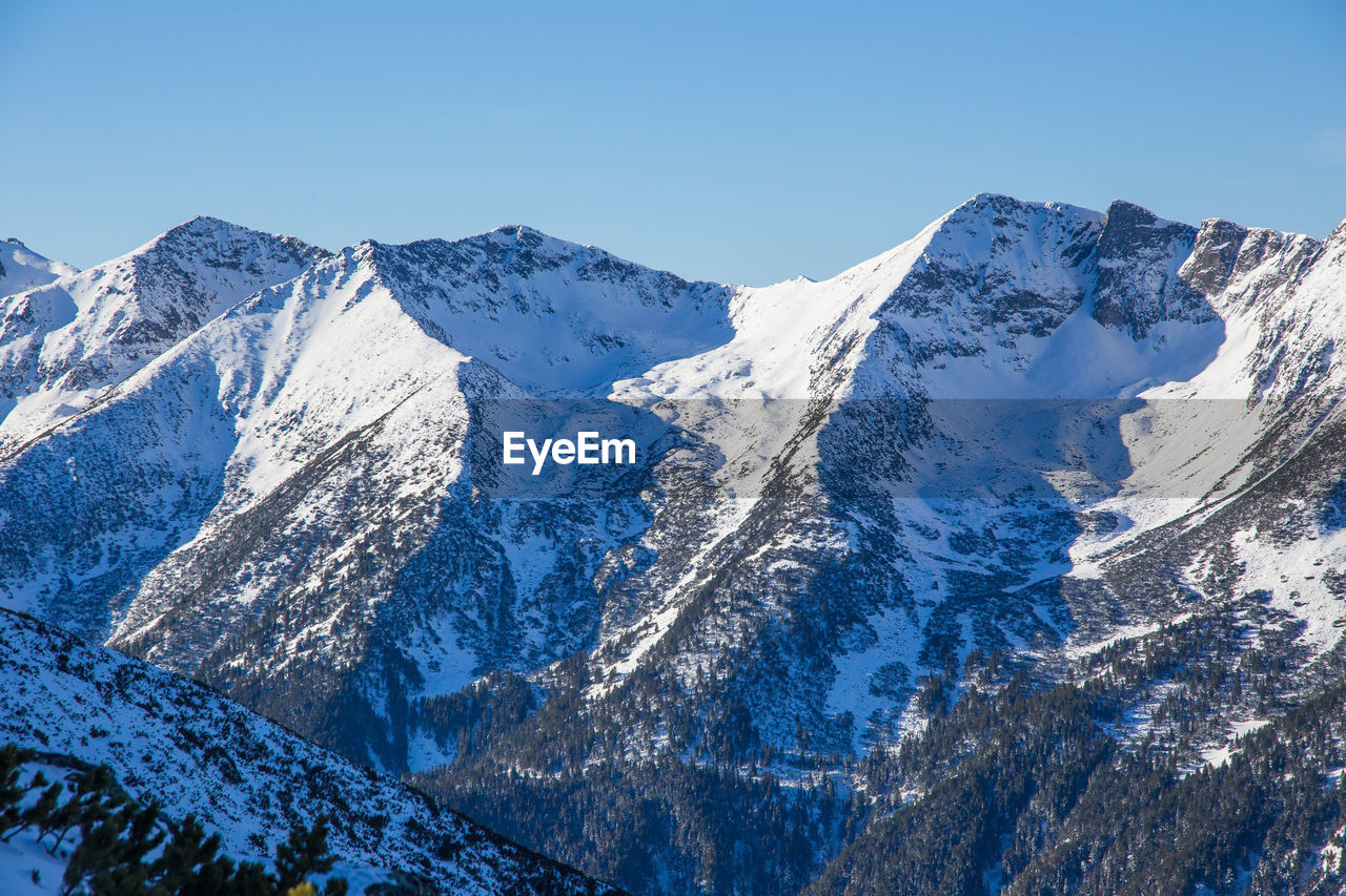 Scenic view of snowcapped mountains against clear blue sky