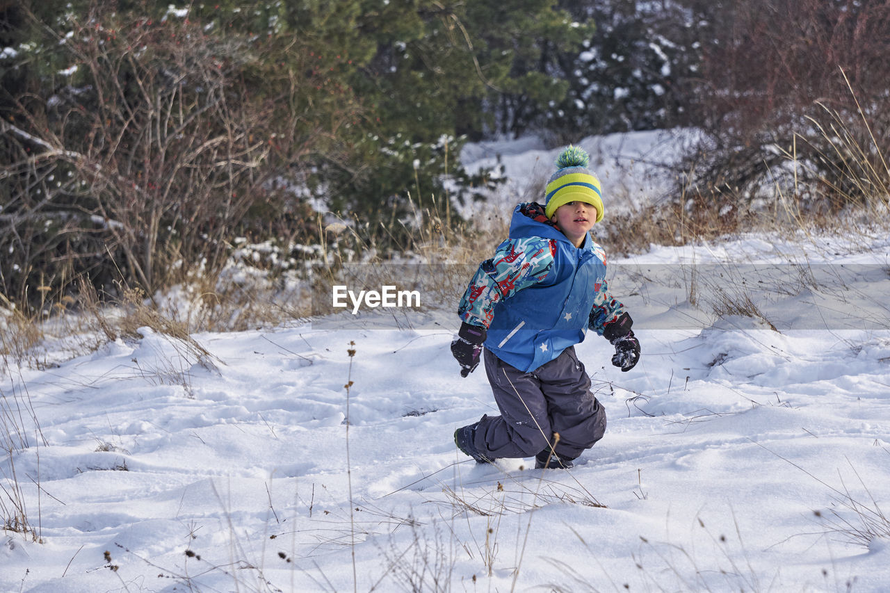 High angle view of boy walking on snow covered field during winter