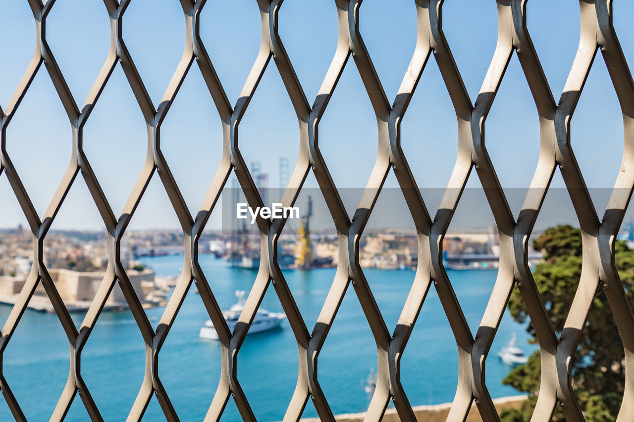 CLOSE-UP OF CHAINLINK FENCE AGAINST BLUE SKY