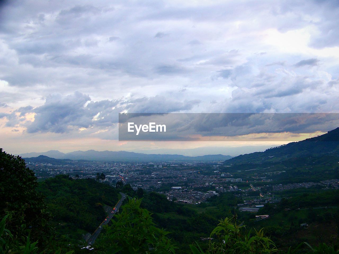 Aerial view of residential district by mountains against cloudy sky