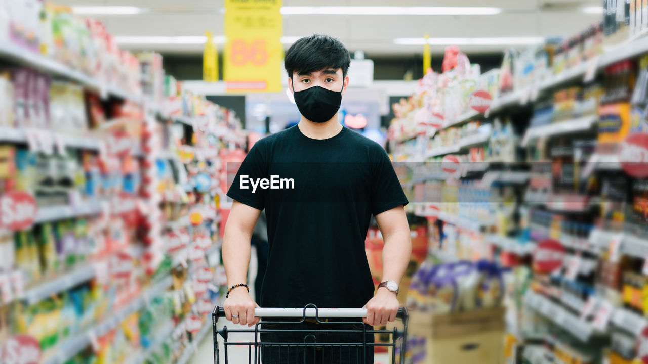 REAR VIEW OF MAN STANDING BY STORE