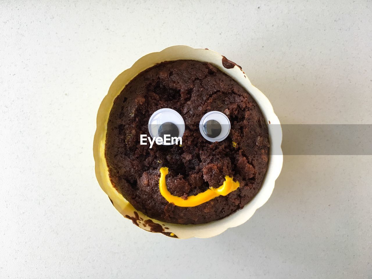 Directly above shot of anthropomorphic face on chocolate muffin