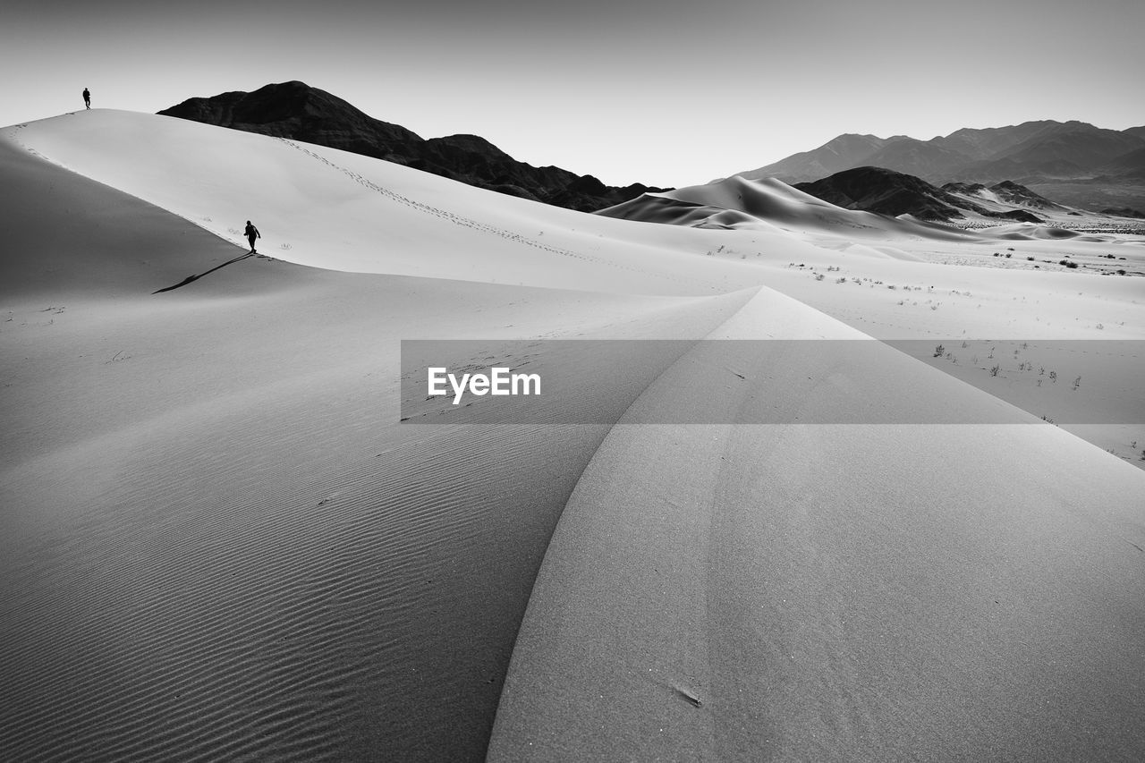 Scenic view of sand dunes and mountains against sky