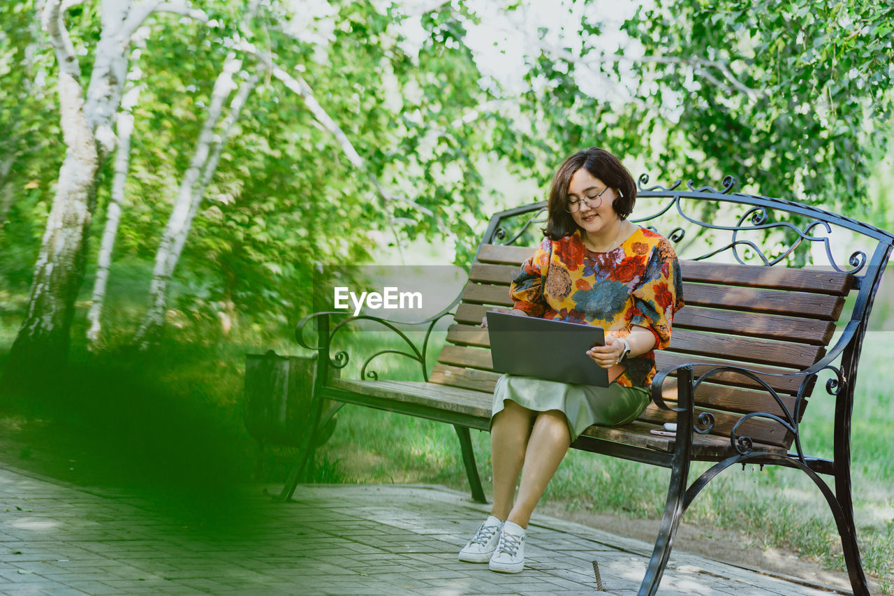 Female professional enjoys remote work on a calm sunny day in a lush green park