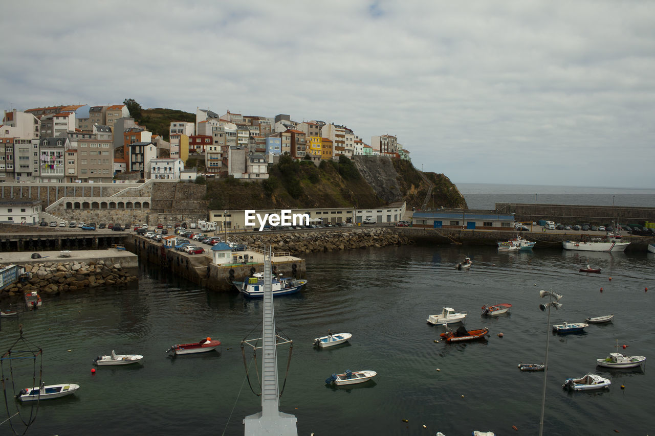 HIGH ANGLE VIEW OF SAILBOATS MOORED ON SEA AGAINST BUILDINGS