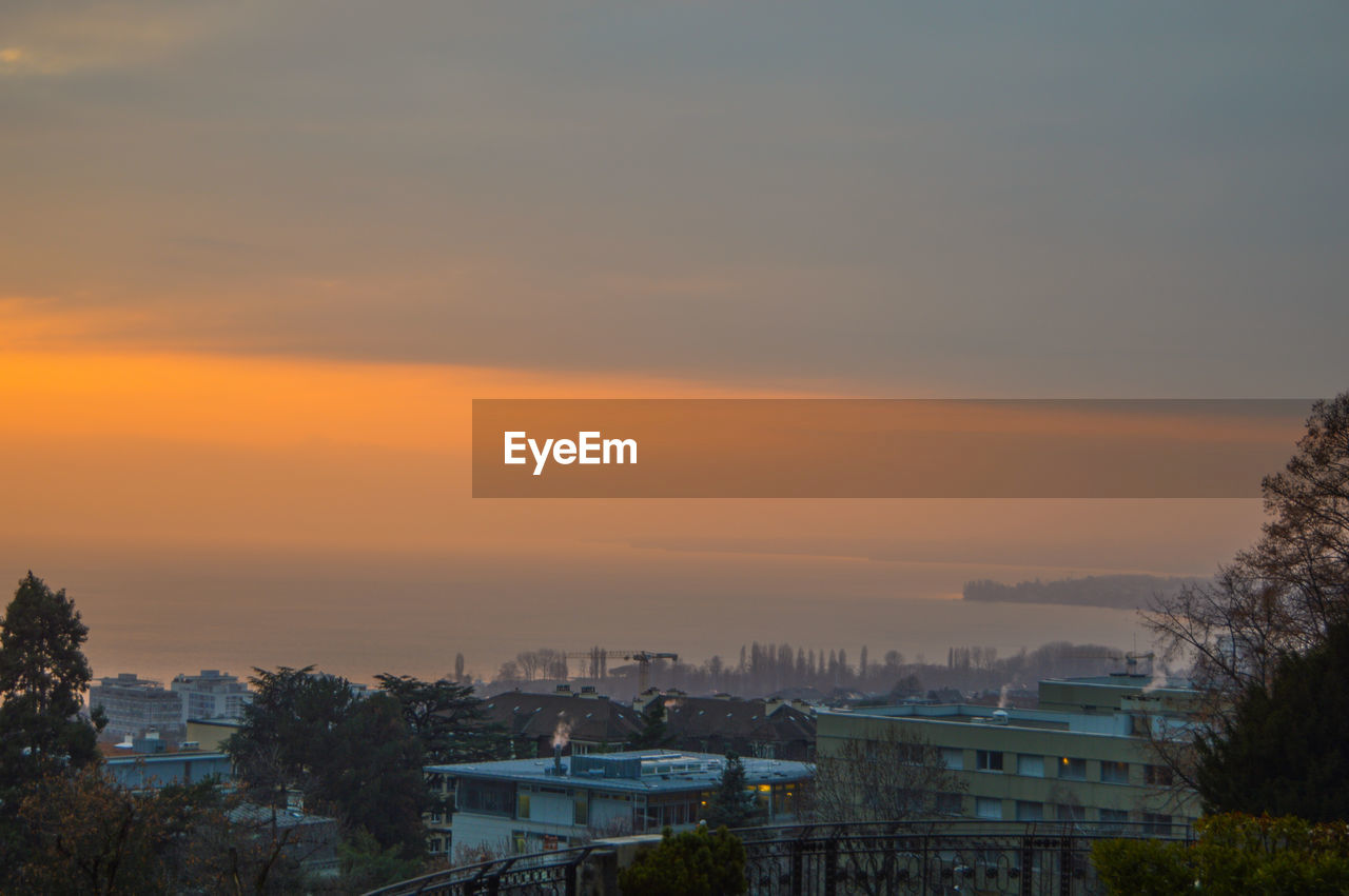 HIGH ANGLE VIEW OF BUILDINGS AGAINST ORANGE SKY