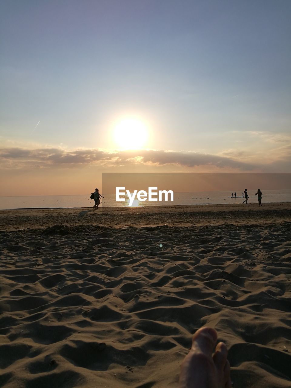 Silhouette people at beach against sky during sunset