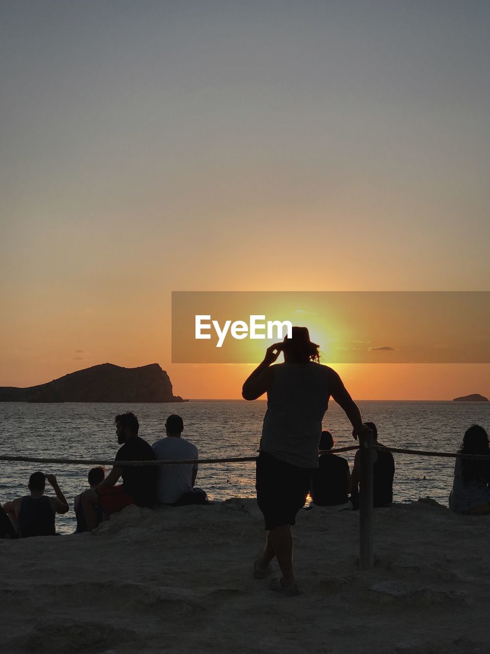 People at beach against sky during sunset