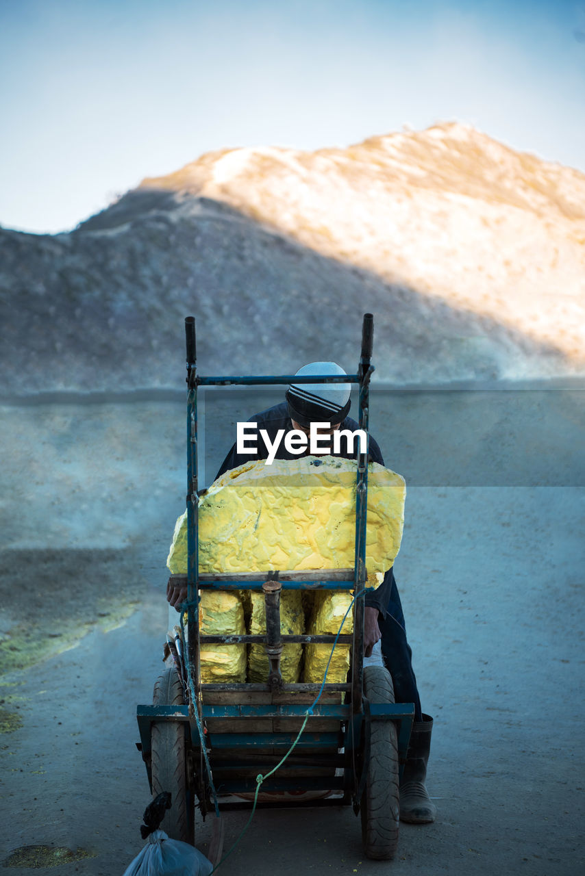 Man standing by rock in cart against mountain