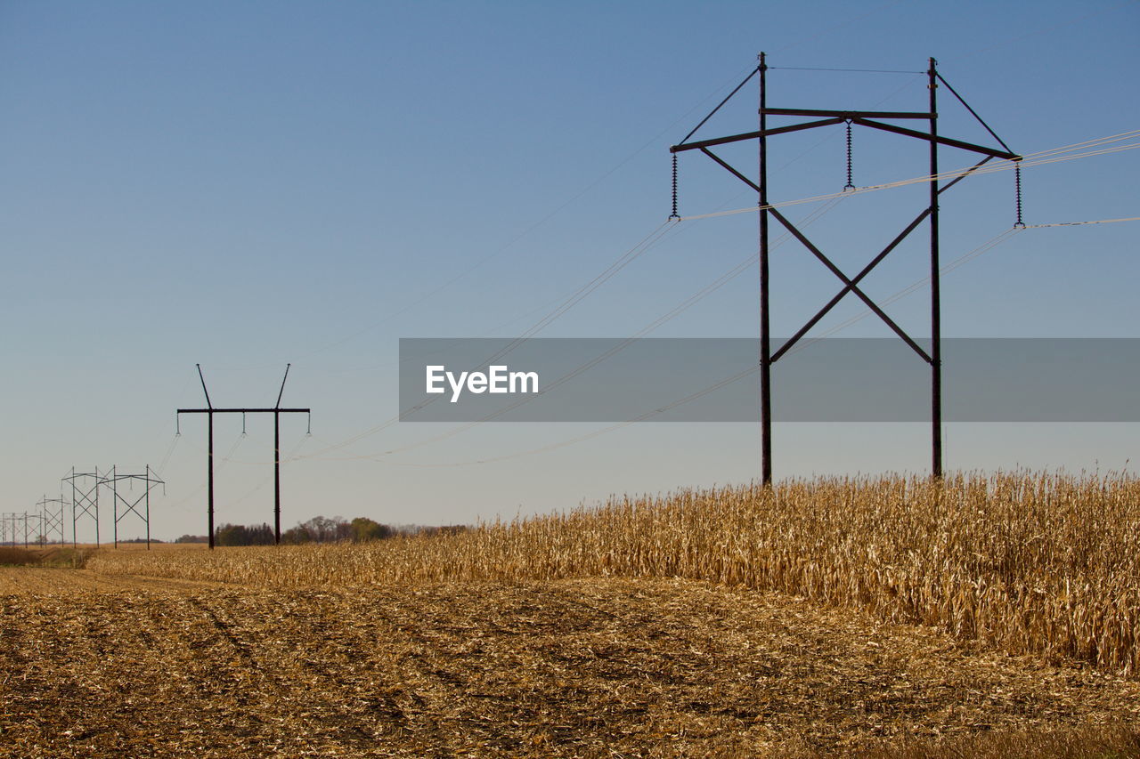 WINDMILLS ON FIELD AGAINST SKY