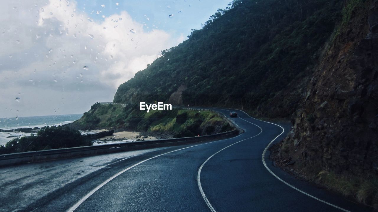 Road by mountains against sky seen through vehicle windshield