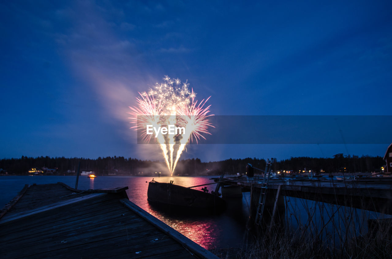 Firework display over river against sky