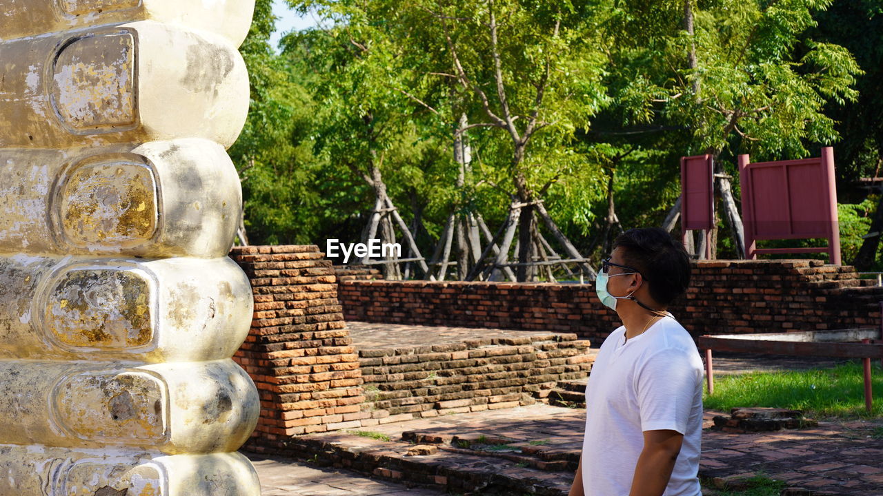 Man wearing mask looking at statue