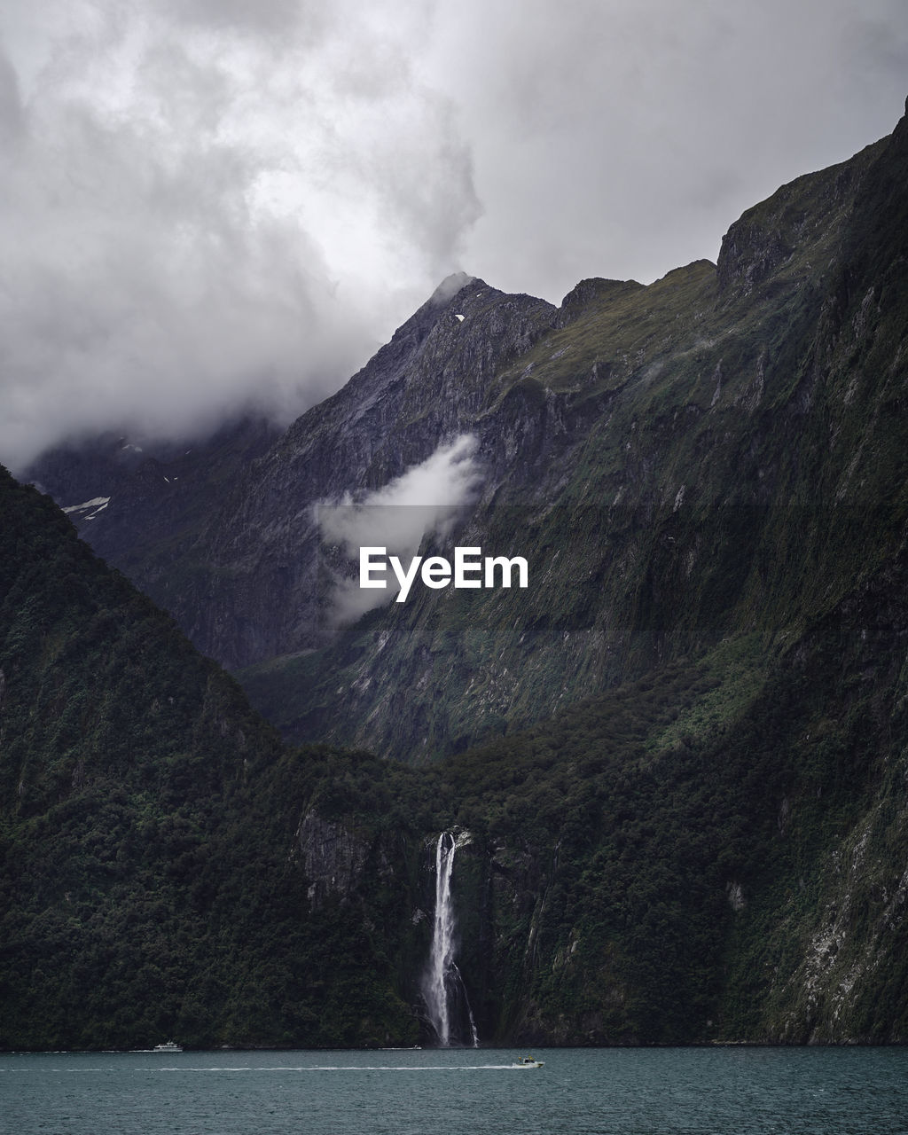 Scenic view of waterfalls through the mountains against a cloudy sky