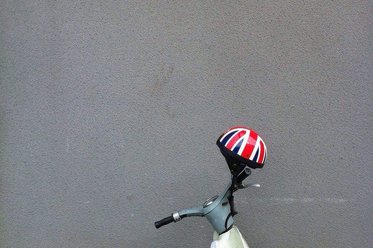 Helmet on scooter against gray wall