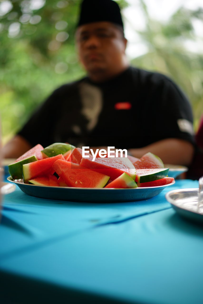 Man having watermelon slices on table