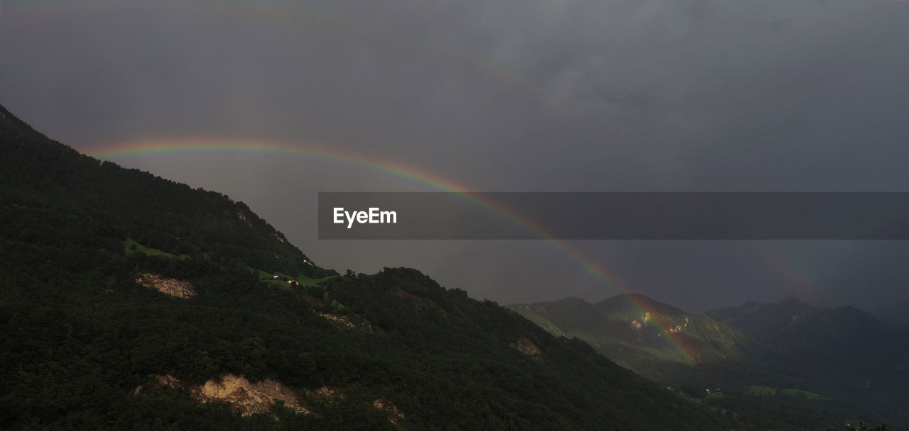 RAINBOW OVER MOUNTAINS AGAINST SKY