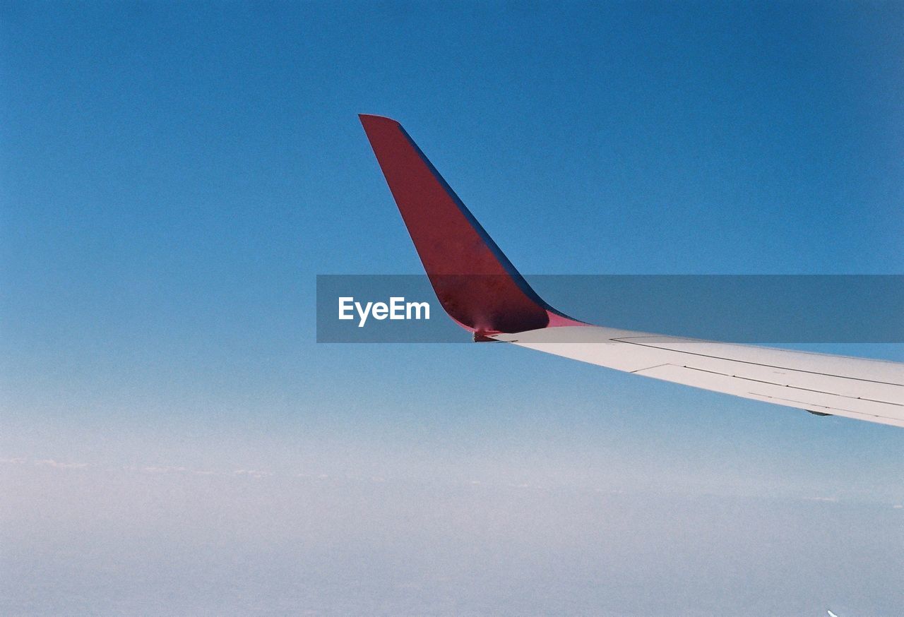 LOW ANGLE VIEW OF AIRPLANE FLYING AGAINST BLUE SKY