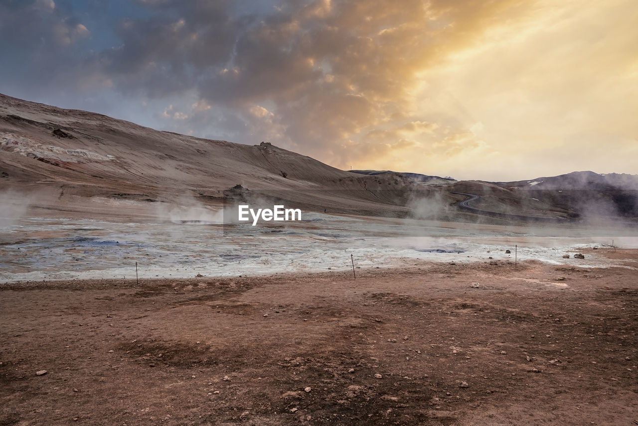 View of steam emitting from crater in geothermal area of hverir during sunset