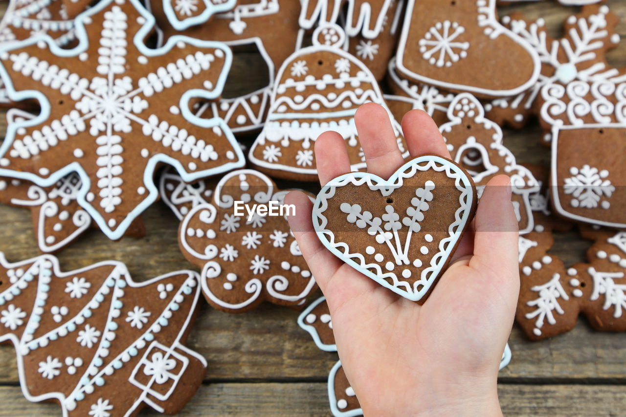 CLOSE-UP OF HAND HOLDING HEART SHAPE MADE OF COOKIES