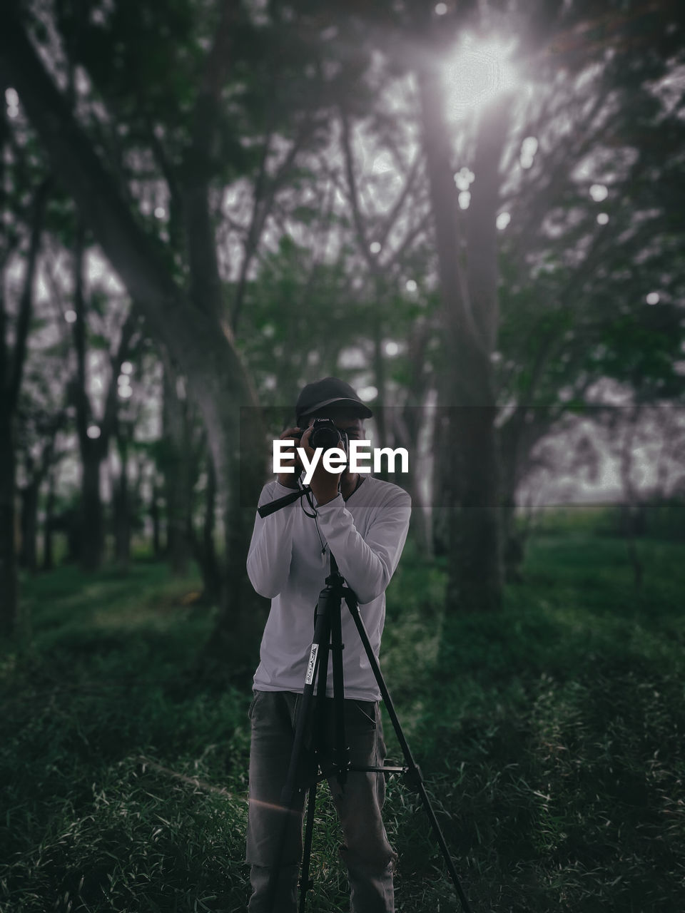 MAN PHOTOGRAPHING WITH UMBRELLA ON FIELD