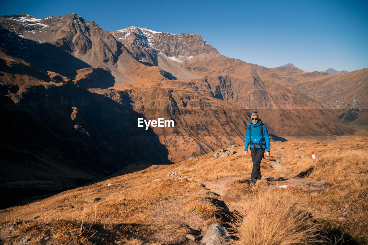 Full length of woman hiking on mountain against sky