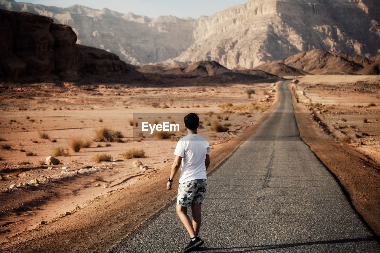 Rear view of man walking on road